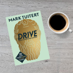 Boek 'DRIVE: Train je stoïcijnse mindset' van Mark Tuitert naast een kopje koffie.