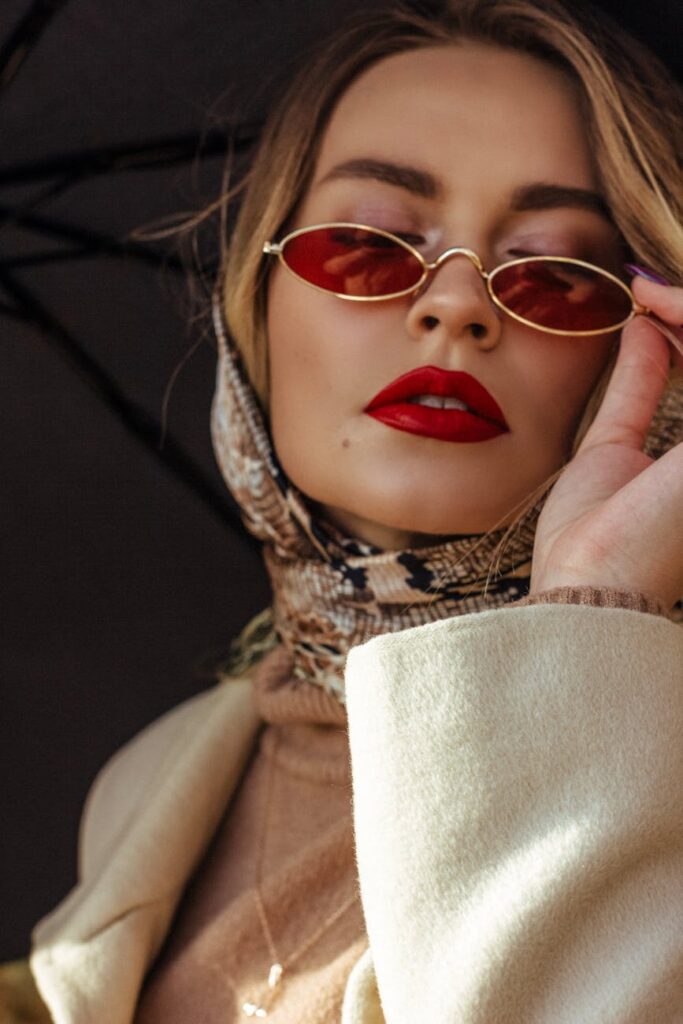 fashionable young woman adjusting sunglasses on street